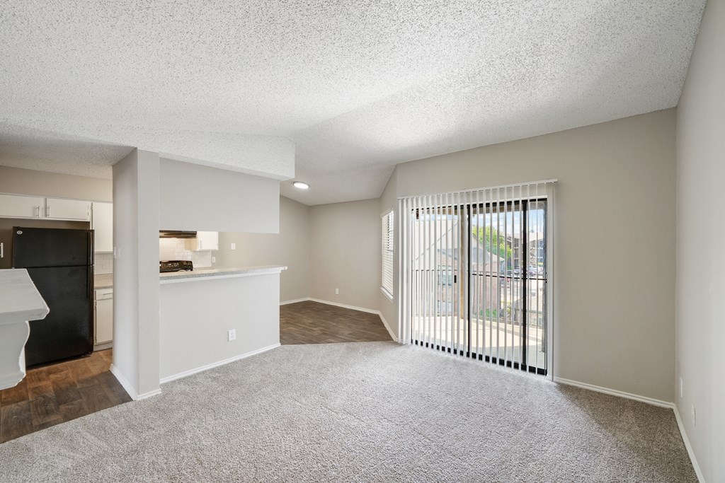 a spacious living room with a kitchen in the background