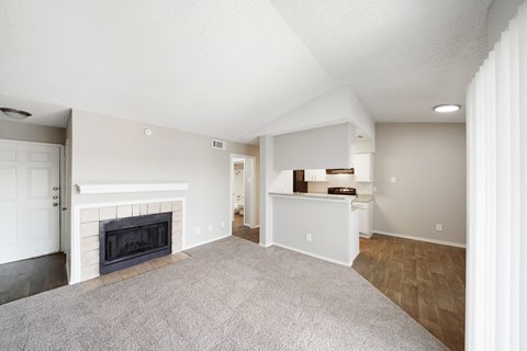 a living room with a fireplace and a kitchen in the background