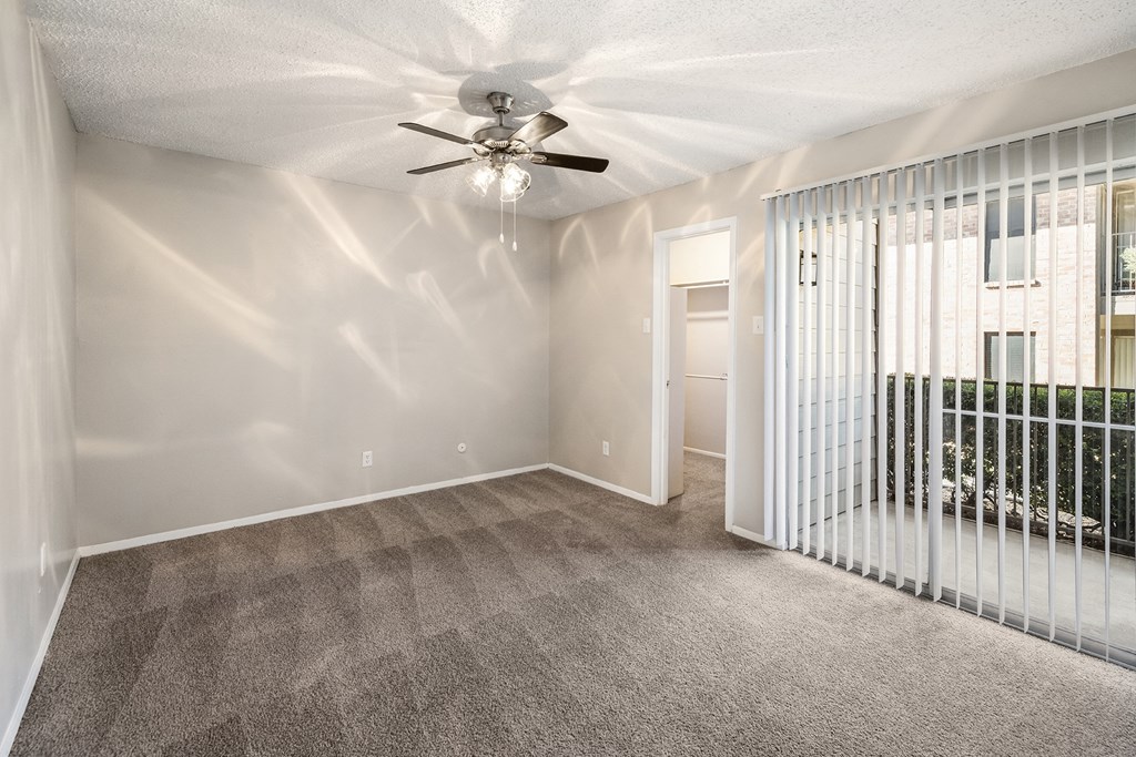 an empty living room with a window and a ceiling fan