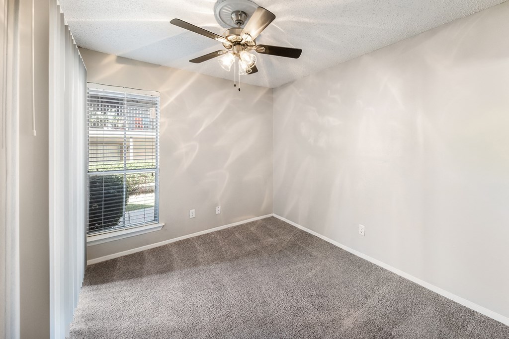 an empty bedroom with a ceiling fan and a window