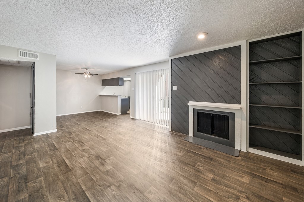 an empty living room with a fireplace and a bookshelf