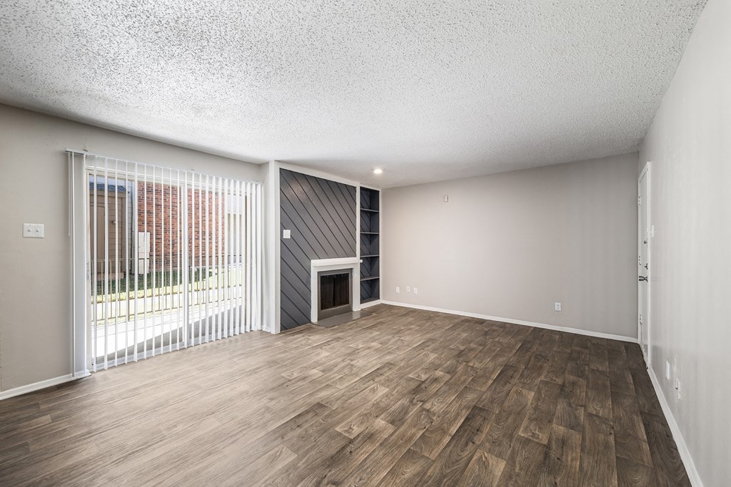 an empty living room with a fireplace and a sliding glass door