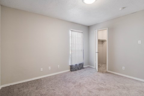 an empty room with carpet and a door to a closet