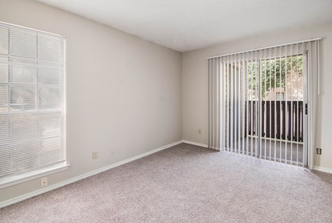 an empty living room with a large window and blinds on the window