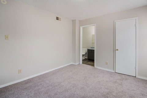 an empty living room with carpet and a door to a bathroom