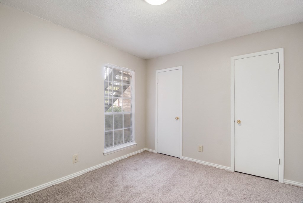 an empty living room with a window and a door to a closet