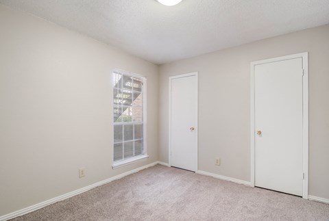 an empty living room with a window and a door to a closet