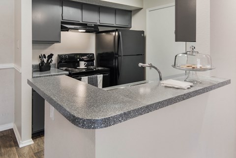 a kitchen with a granite counter top and a black refrigerator