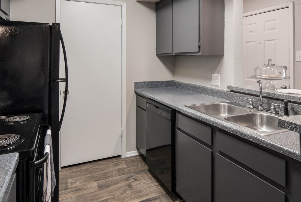 a kitchen with black appliances and gray counter tops and a black refrigerator