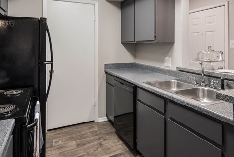 a kitchen with black appliances and gray counter tops and a black refrigerator
