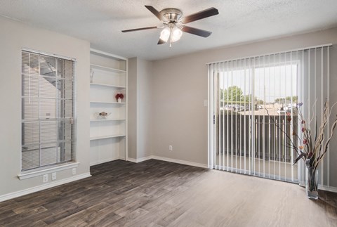 an empty living room with a large window and a ceiling fan