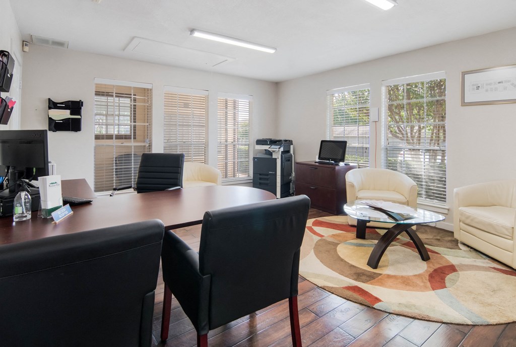 an office with a desk and chairs and a living room