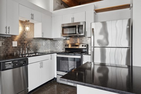 a white kitchen with stainless steel appliances and black counter tops