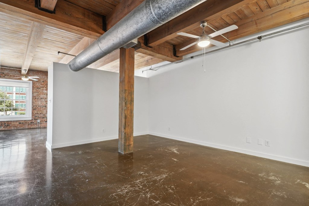 Loft living are with ceiling fan, concrete floors and brick walls | Deep Ellum Lofts in Dallas, TX