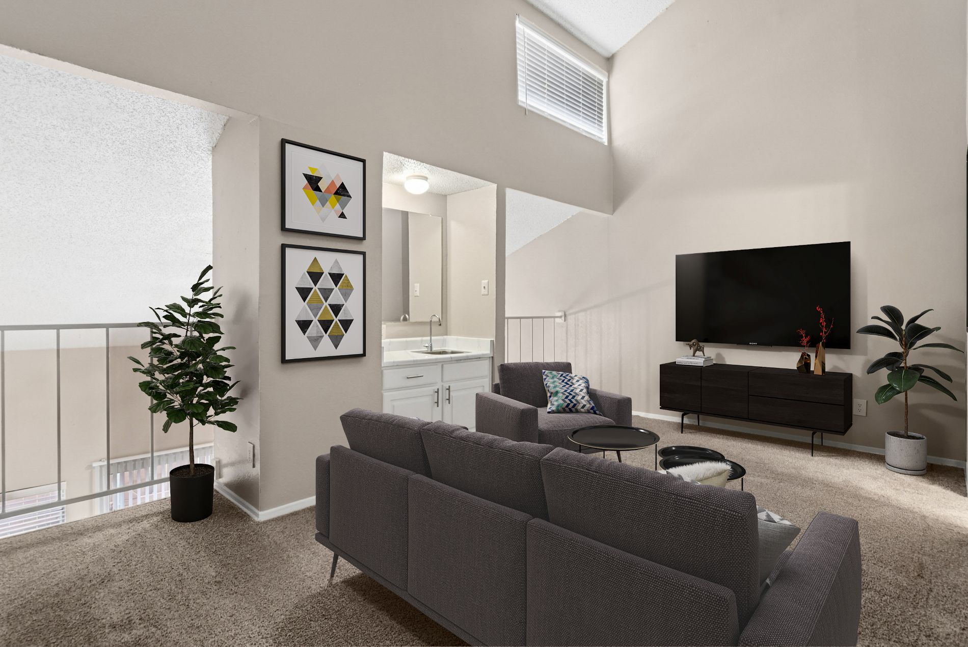 A living room with a grey couch and a flat screen TV mounted on the wall.
