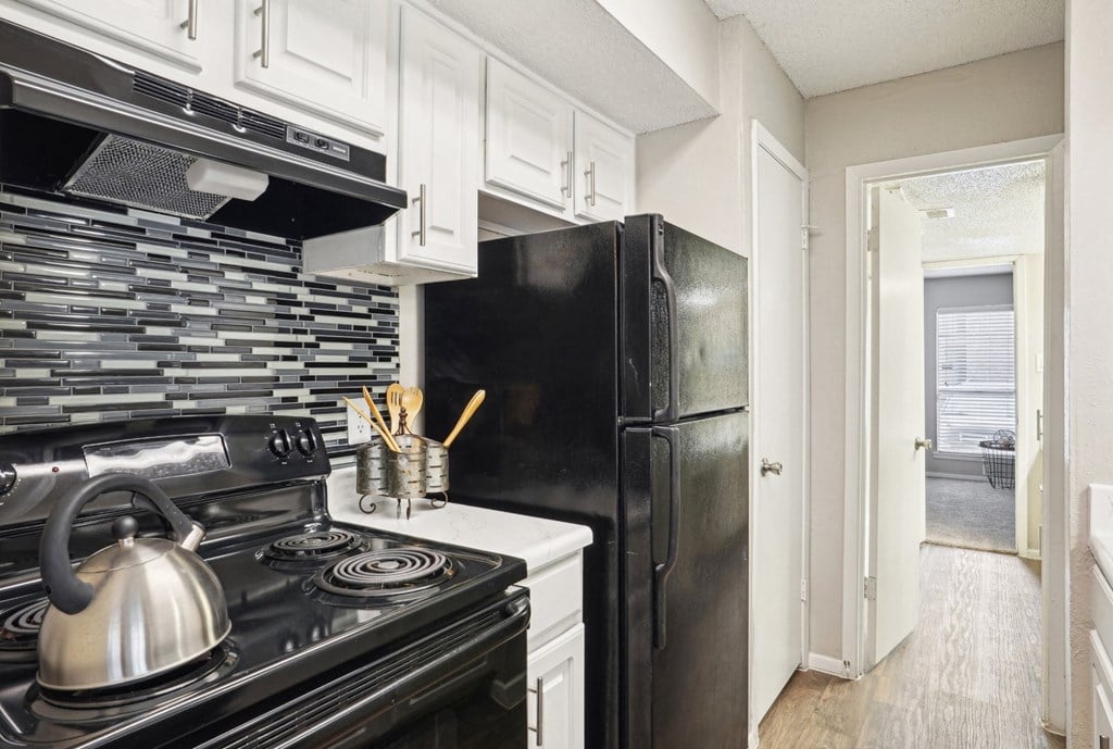 Model A2 floor plan kitchen with black appliances, tile backsplash, and white cabinets Noel on The Parkway in Dallas, TX