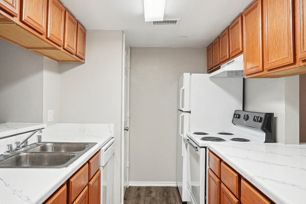 Unfurnished A4 floor plan kitchen with white appliances and wooden cabinets Noel on The Parkway in Dallas, TX