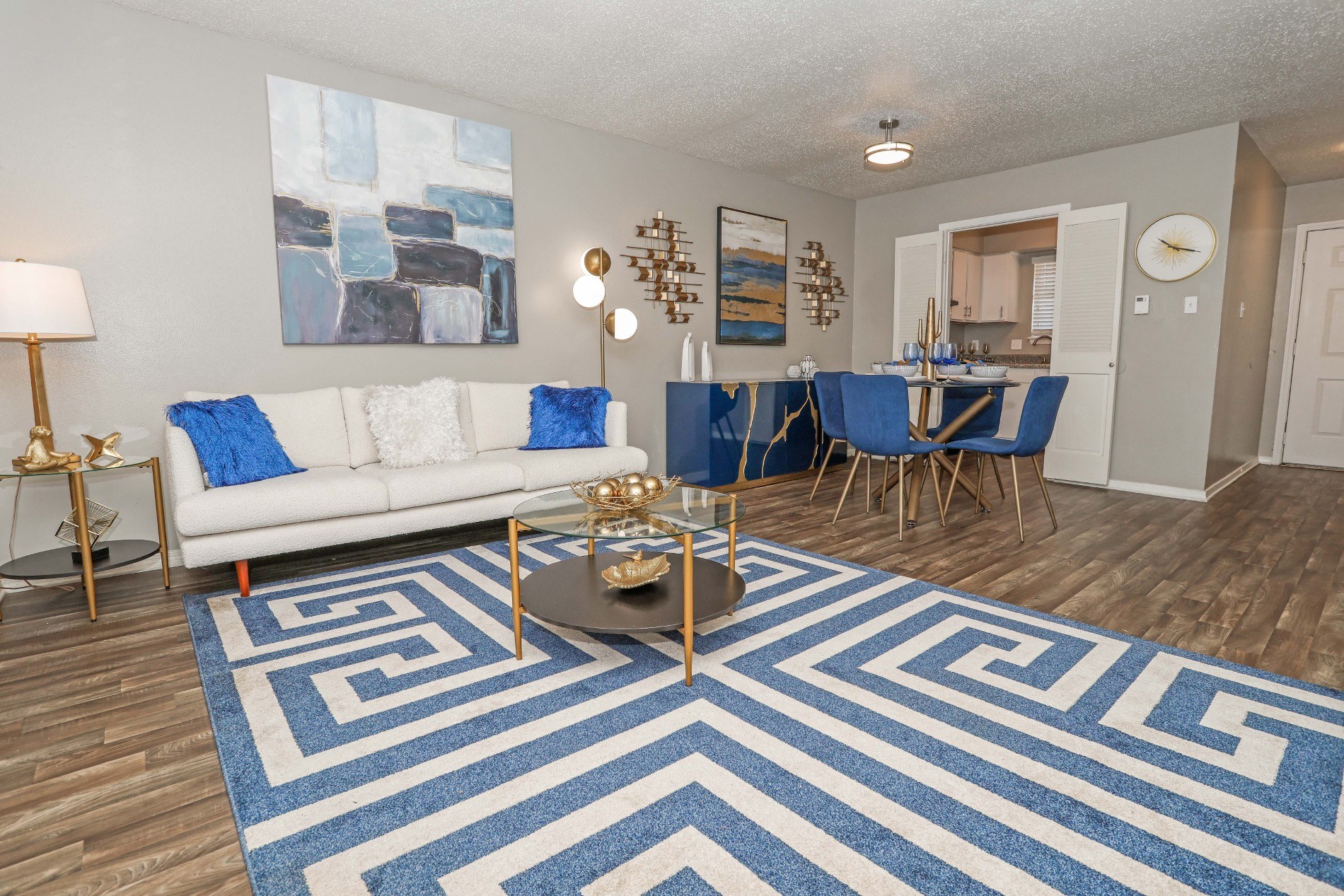 A living room with a white couch and a blue and white rug.