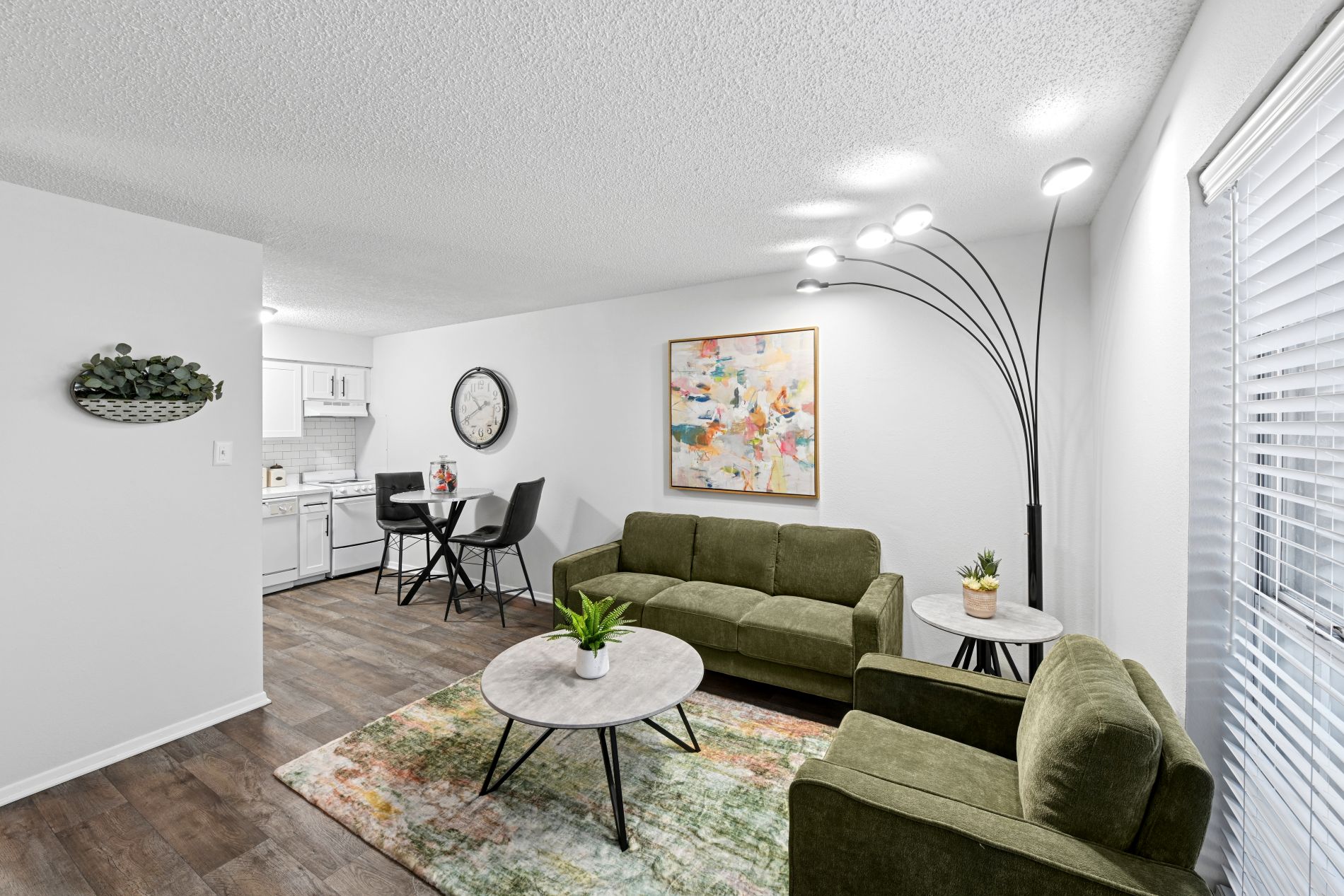 A living room with a green couch, a coffee table, and a painting on the wall.