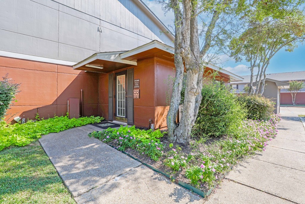 Leasing office with flowers growing next to the sidewalk at Orleans Square in Shreveport, LA