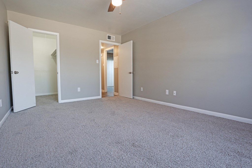 A room with a carpeted floor, ceiling fan, and gray walls at Orleans Square in Shreveport, LA