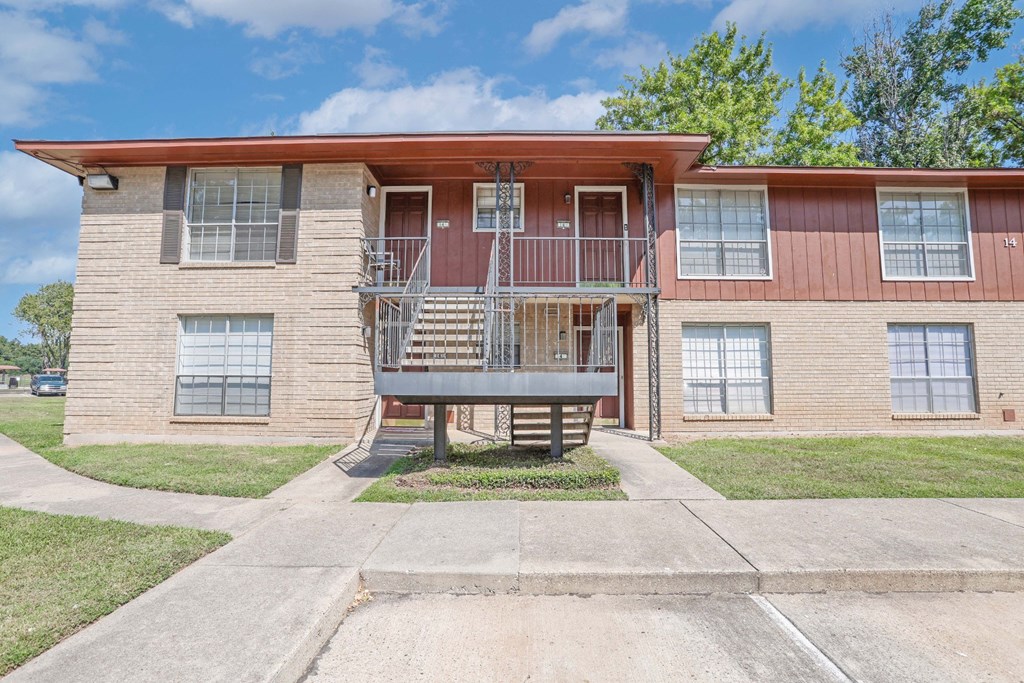 A two-story apartment building with a red roof and a stairway to the second floor at Orleans Square in Shreveport, LA