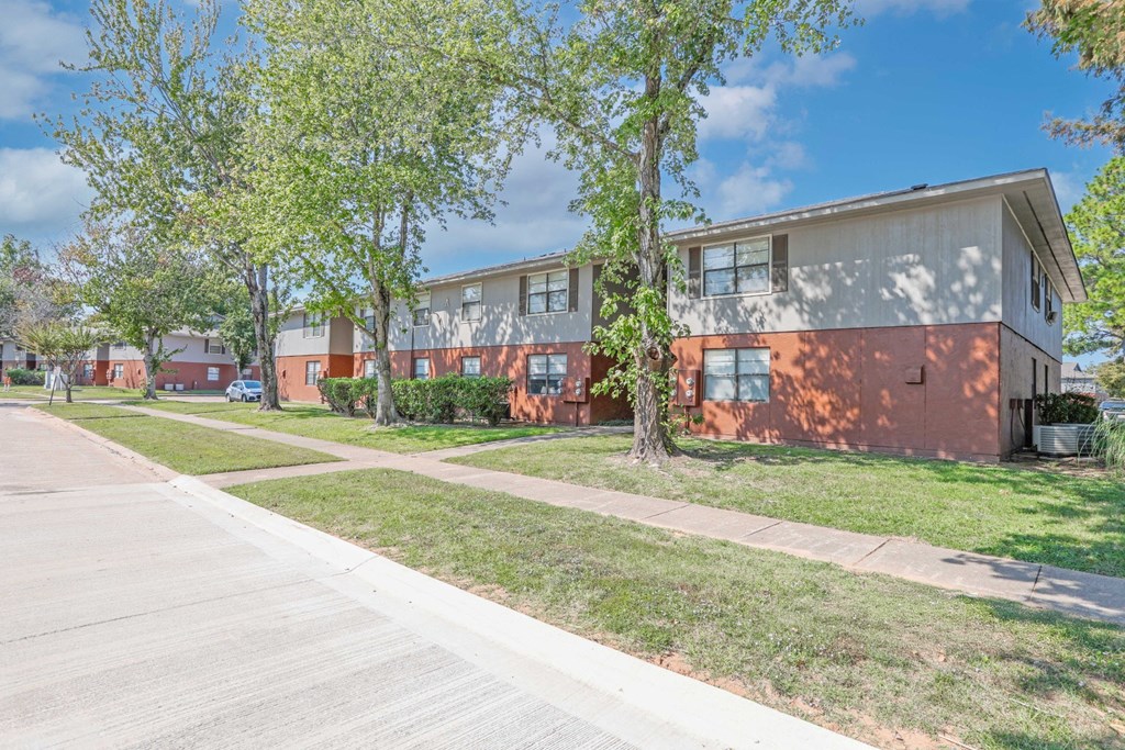 A sidewalk and lawn next to apartment buildings at Orleans Square in Shreveport, LA