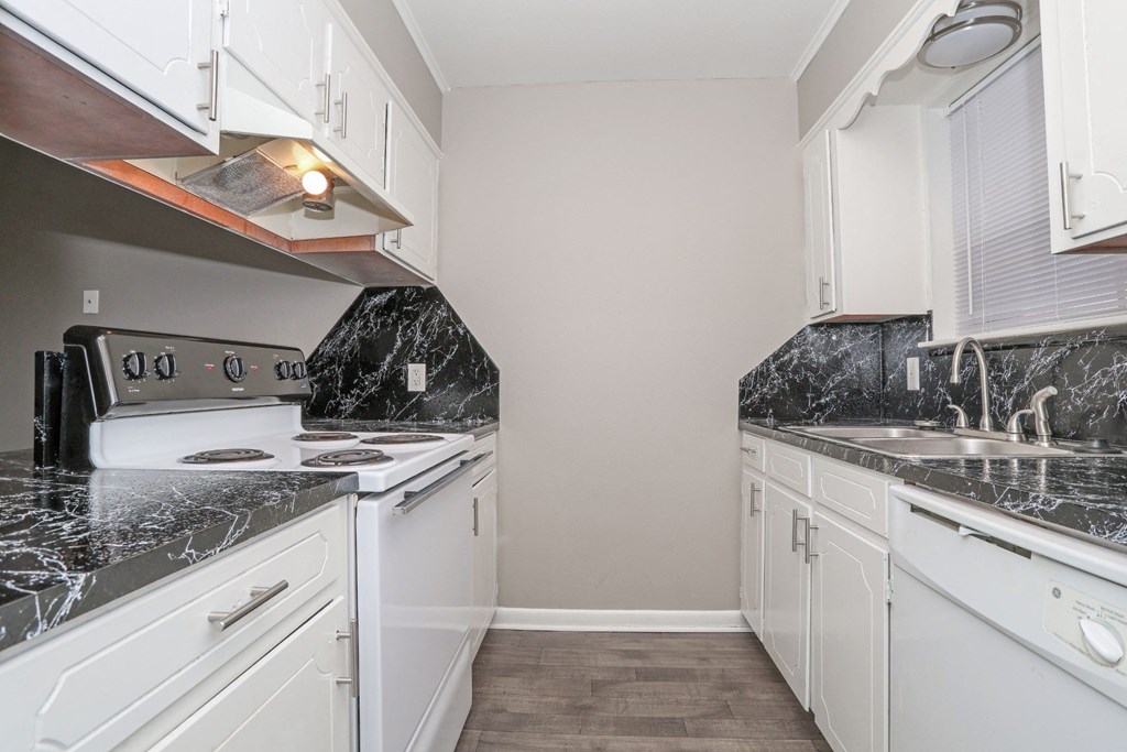 A kitchen with white cabinets, a stove top oven, sink, and dishwasher at Orleans Square in Shreveport, LA