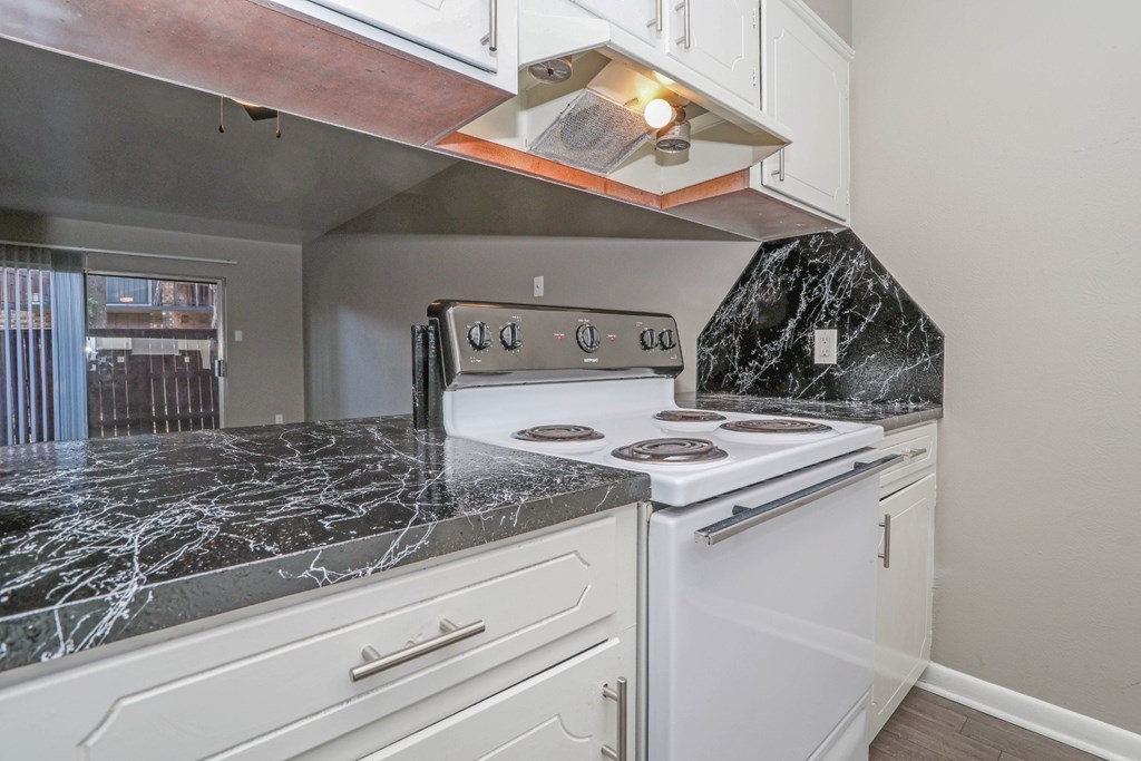 A kitchen with a white oven/stove and a dark marble countertop at Orleans Square in Shreveport, LA