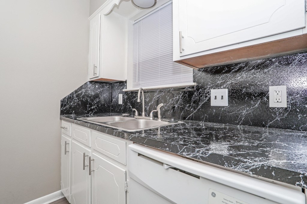 A kitchen with a marble countertop and white cabinets at Orleans Square in Shreveport, LA