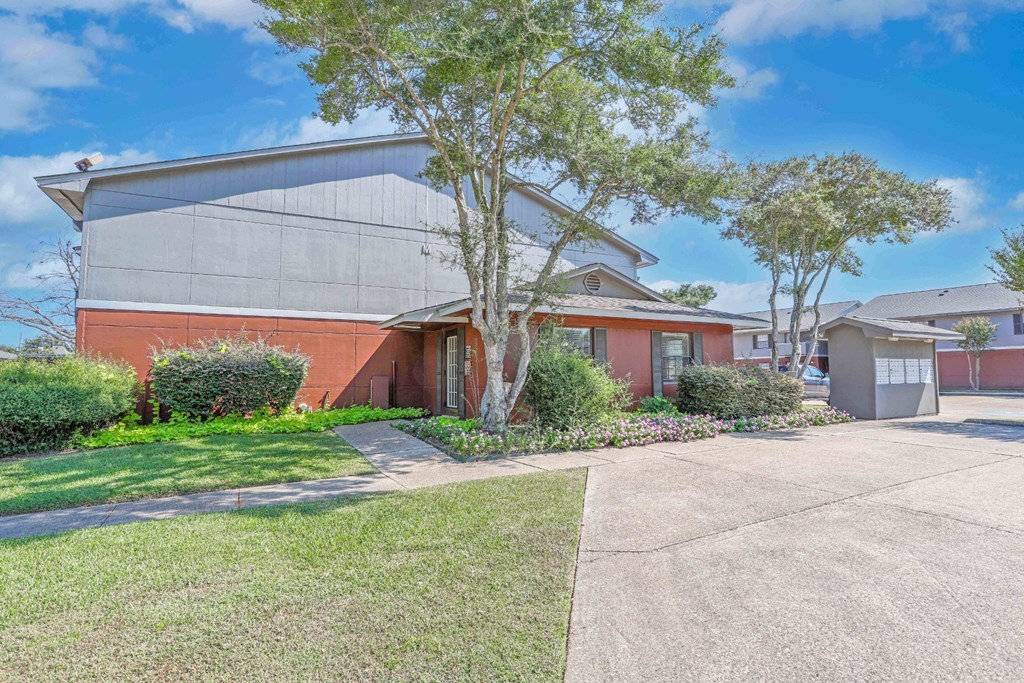 The leasing office with a grey roof and a tree in front at Orleans Square in Shreveport, LA