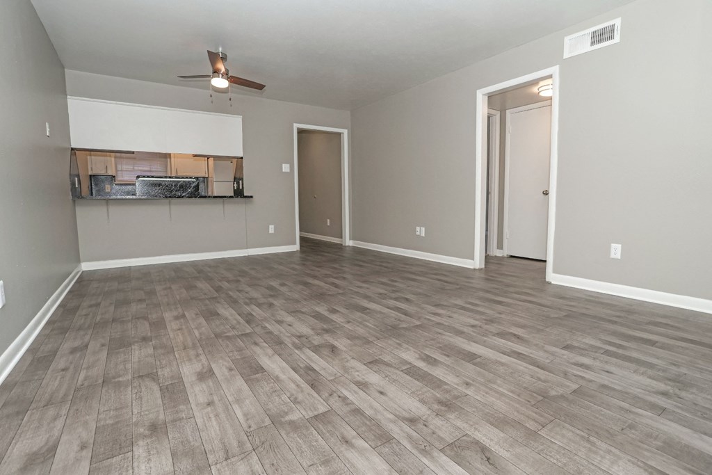 A living room with a ceiling fan and light, and a wooden floor at Orleans Square in Shreveport, LA