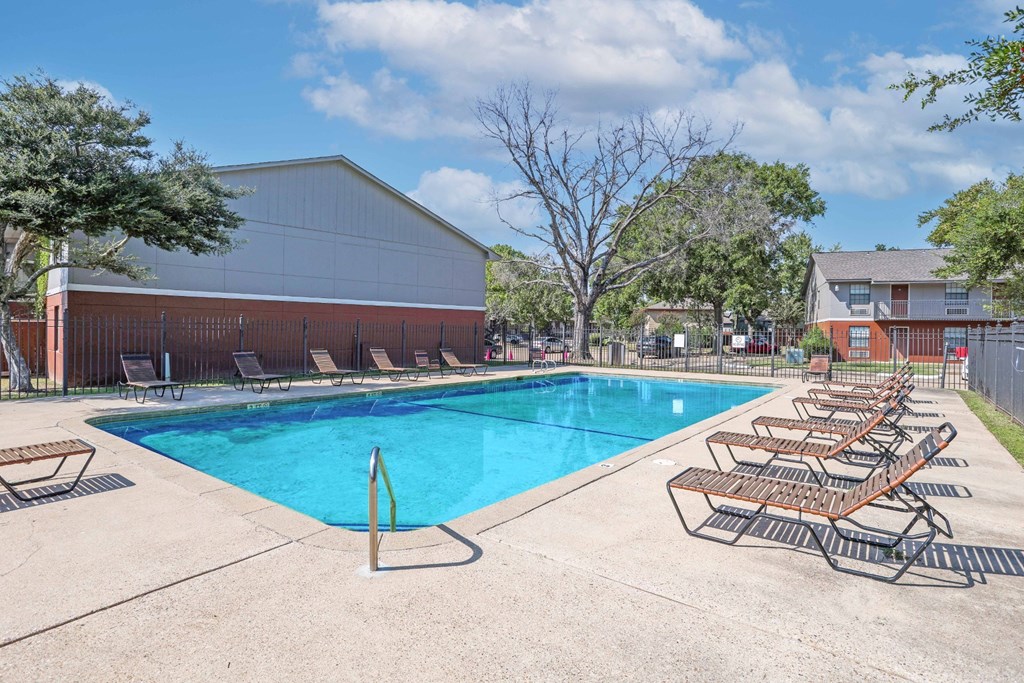 A pool with sun loungers and apartment buildings in the background at Orleans Square in Shreveport, LA