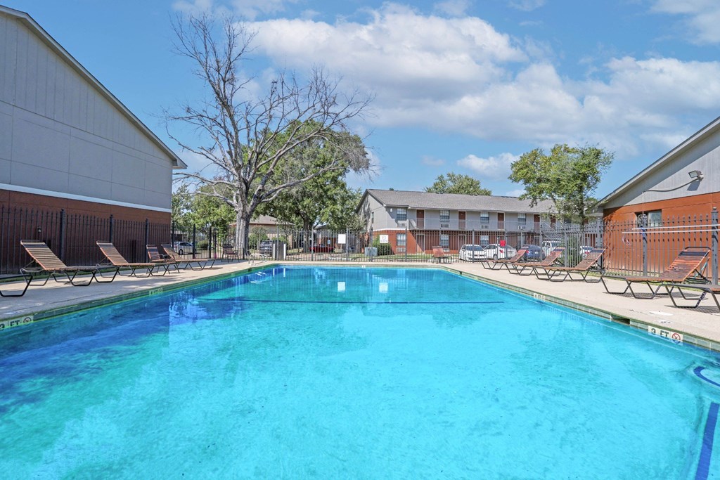 A large swimming pool with lounge chairs and apartment buildings in the background at Orleans Square in Shreveport, LA