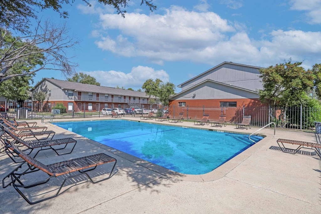 A swimming pool surrounded by lounge chairs and a fence at Orleans Square in Shreveport, LA