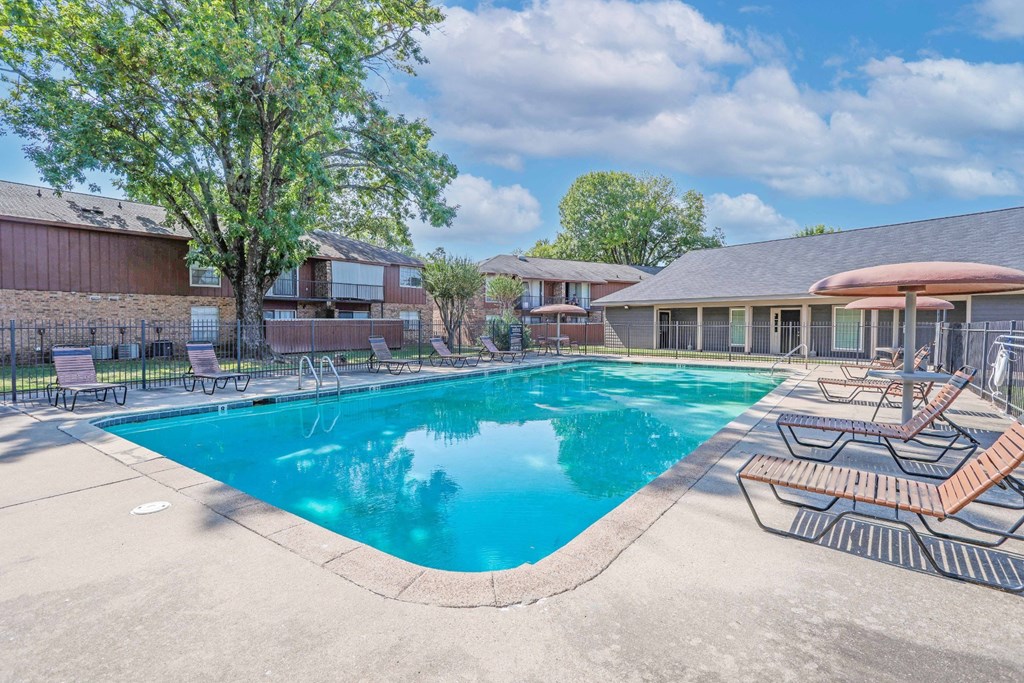 A swimming pool surrounded by a concrete patio and lounge chairs at Orleans Square in Shreveport, LA
