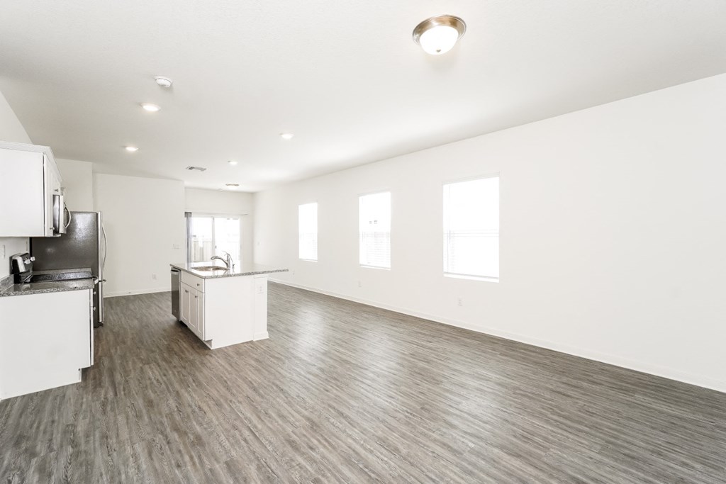 an empty living room with a kitchen in the background at Beacon at Meridian, San Antonio, 78245