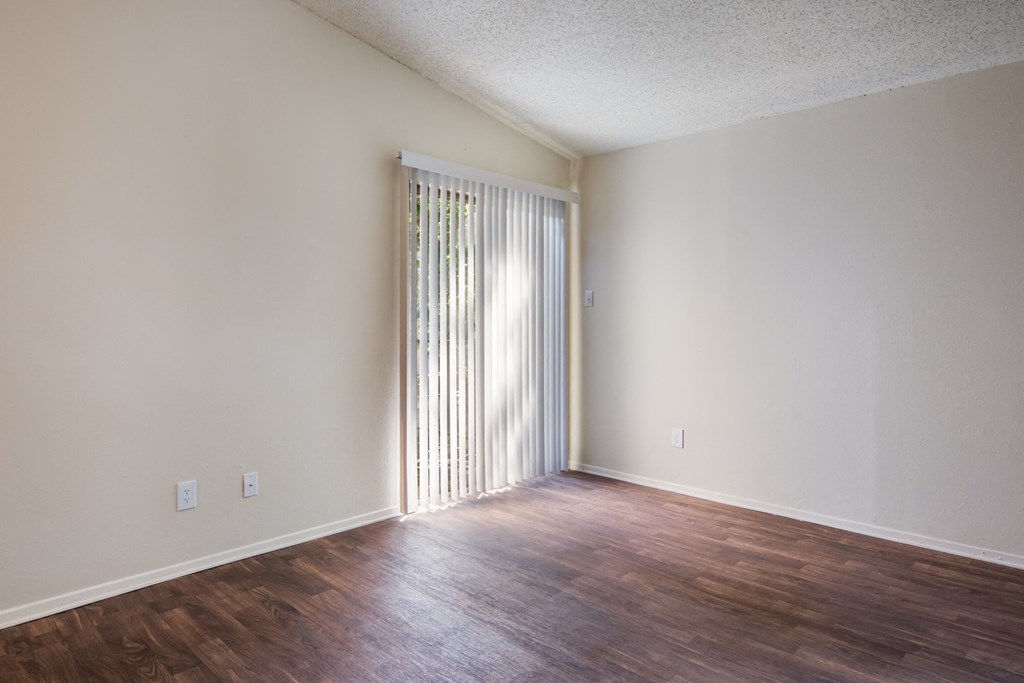 an empty living room with wood flooring and a sliding glass door