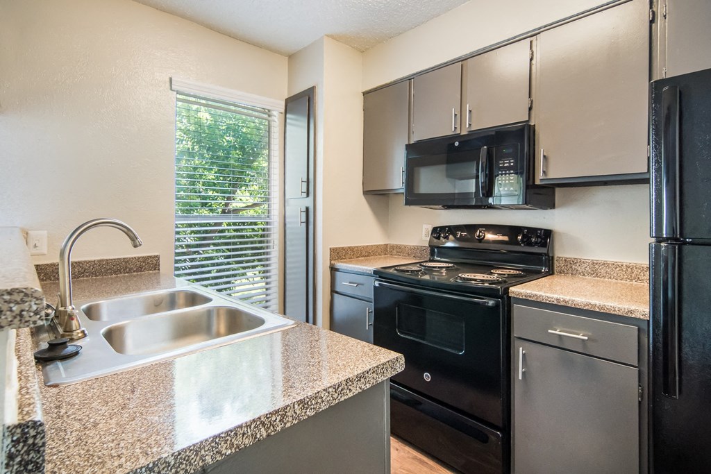 an updated kitchen with granite counter tops and black appliances