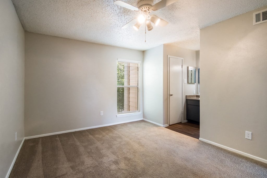 an empty living room with a ceiling fan and a window