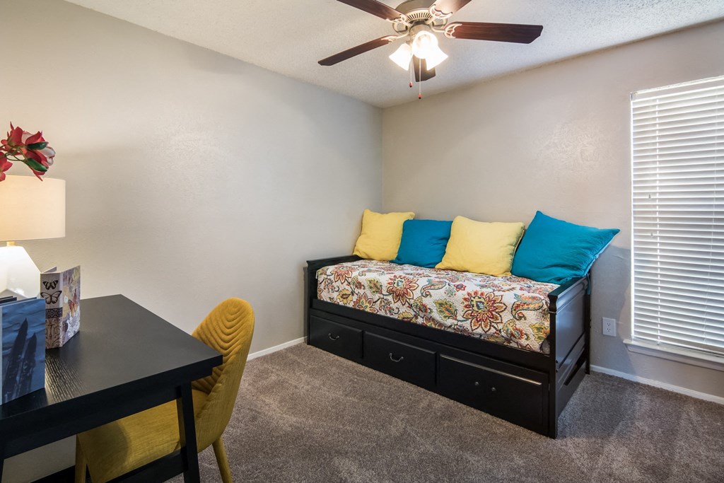 a bedroom with a bed and a table and a ceiling fan