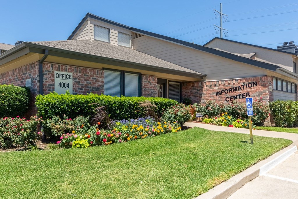 a large brick building with a lawn and flowers in front of it