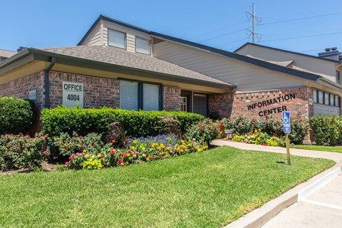 a large brick building with a lawn and flowers in front of it
