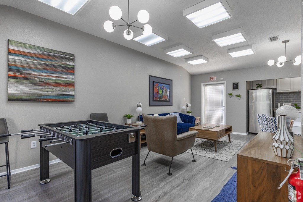 A social room with a foosball table and a couch at Preston Oaks Apartments in Dallas, TX.
