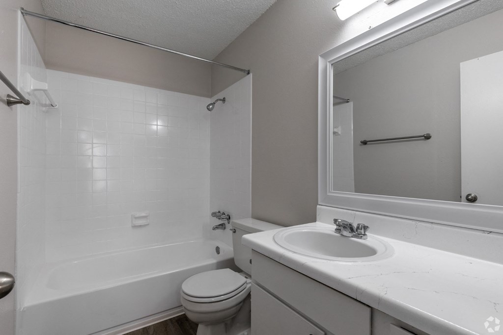 A white bathroom with a toilet, sink, and bathtub at Preston Oaks Apartments in Dallas, TX.