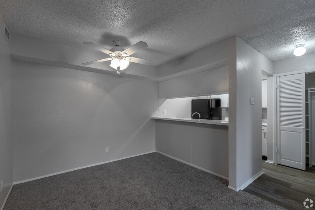 A dining room with a ceiling fan and carpeted floors at Preston Oaks Apartments in Dallas, TX.