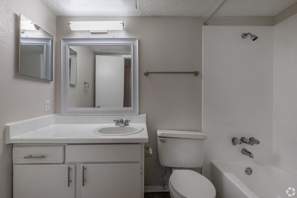 A white bathroom with a sink, toilet, and bathtub at Preston Oaks Apartments in Dallas, TX.
