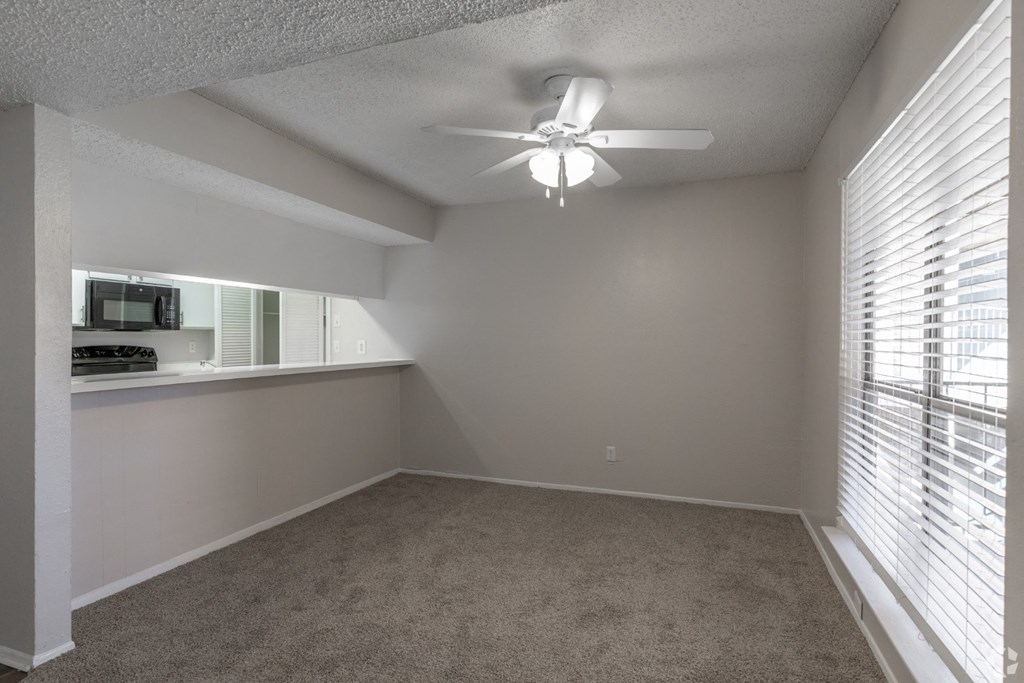 A dining room with a ceiling fan and carpeted floor at Preston Oaks Apartments in Dallas, TX.