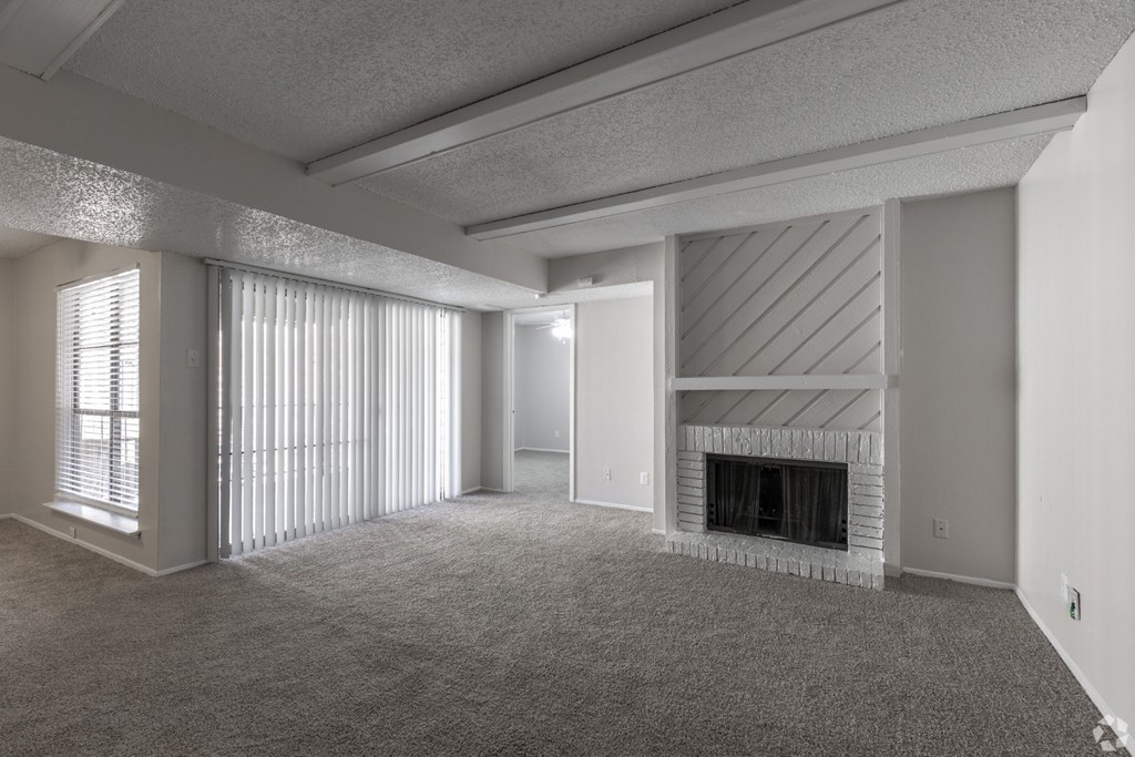 A living room with a fireplace and sliding glass doors at Preston Oaks Apartments in Dallas, TX.