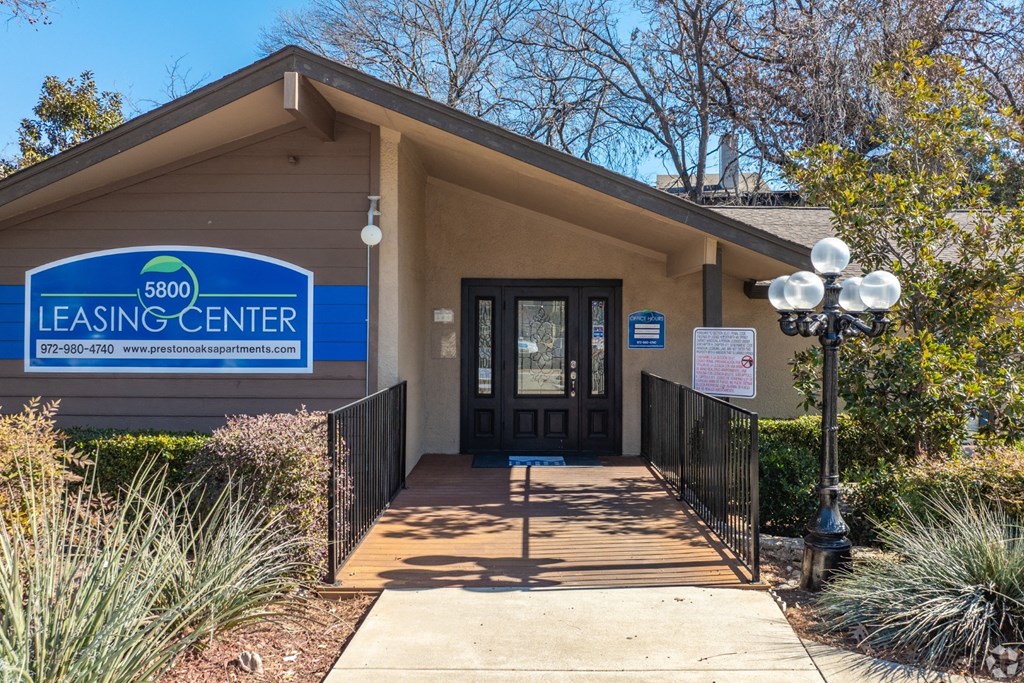 The front of a leasing office with a sign that says Leasing Center at Preston Oaks Apartments in Dallas, TX.